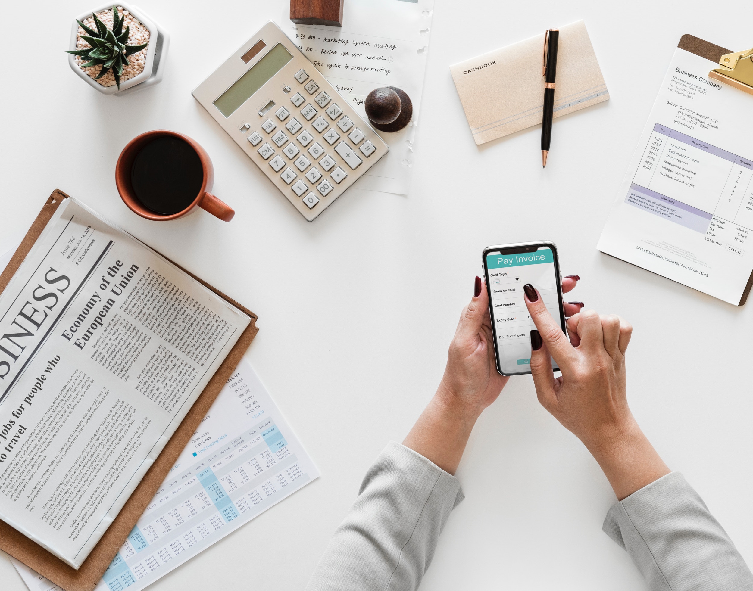 woman holding a cell phone and working at her desk
