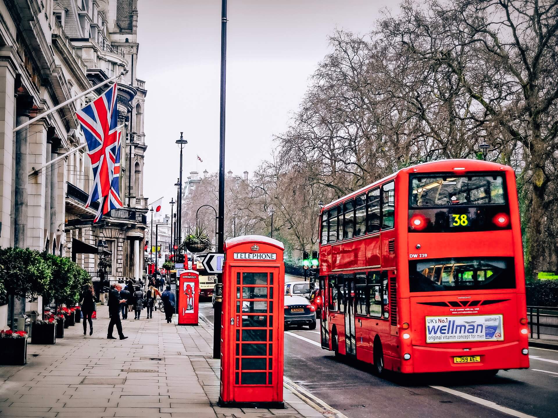 Red bus on London street parked by a telephone booth