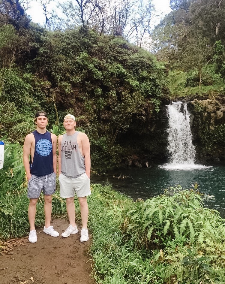 Two boys standing in front of a waterfall in Maui, Hawaii