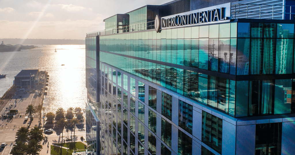 Glass windowed exterior of hotel with bay in the background.
