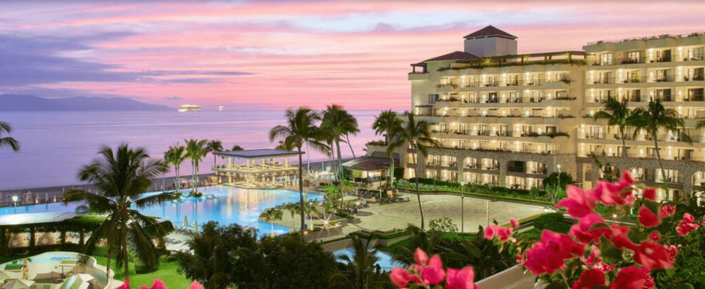 pIcture of big hotel on the beach with palm trees