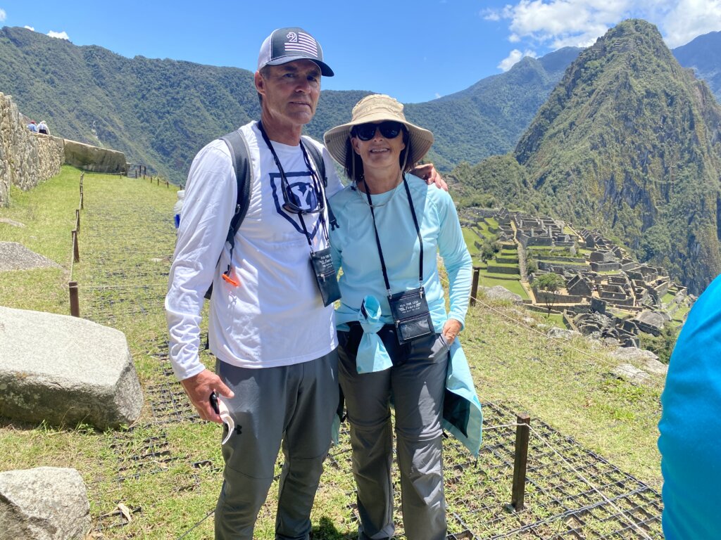 Man and woman standing in front of large mountain and ruins