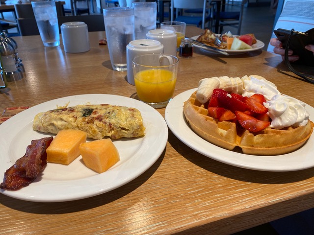 2 white plates with breakfast and orange juice in glass