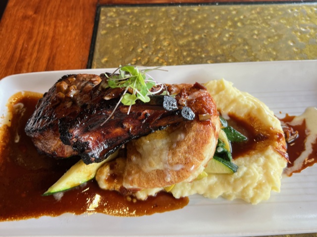 Pork chop and mashed potatoes on white rectangular plate