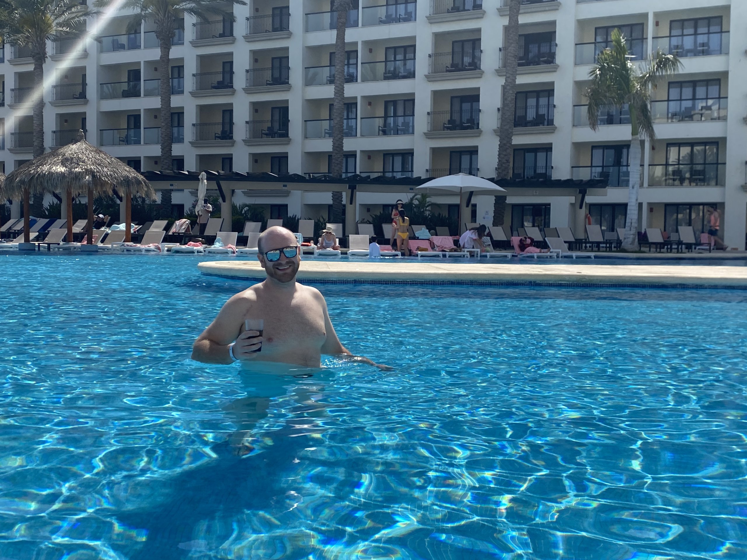 Man walking in pool holding beverage