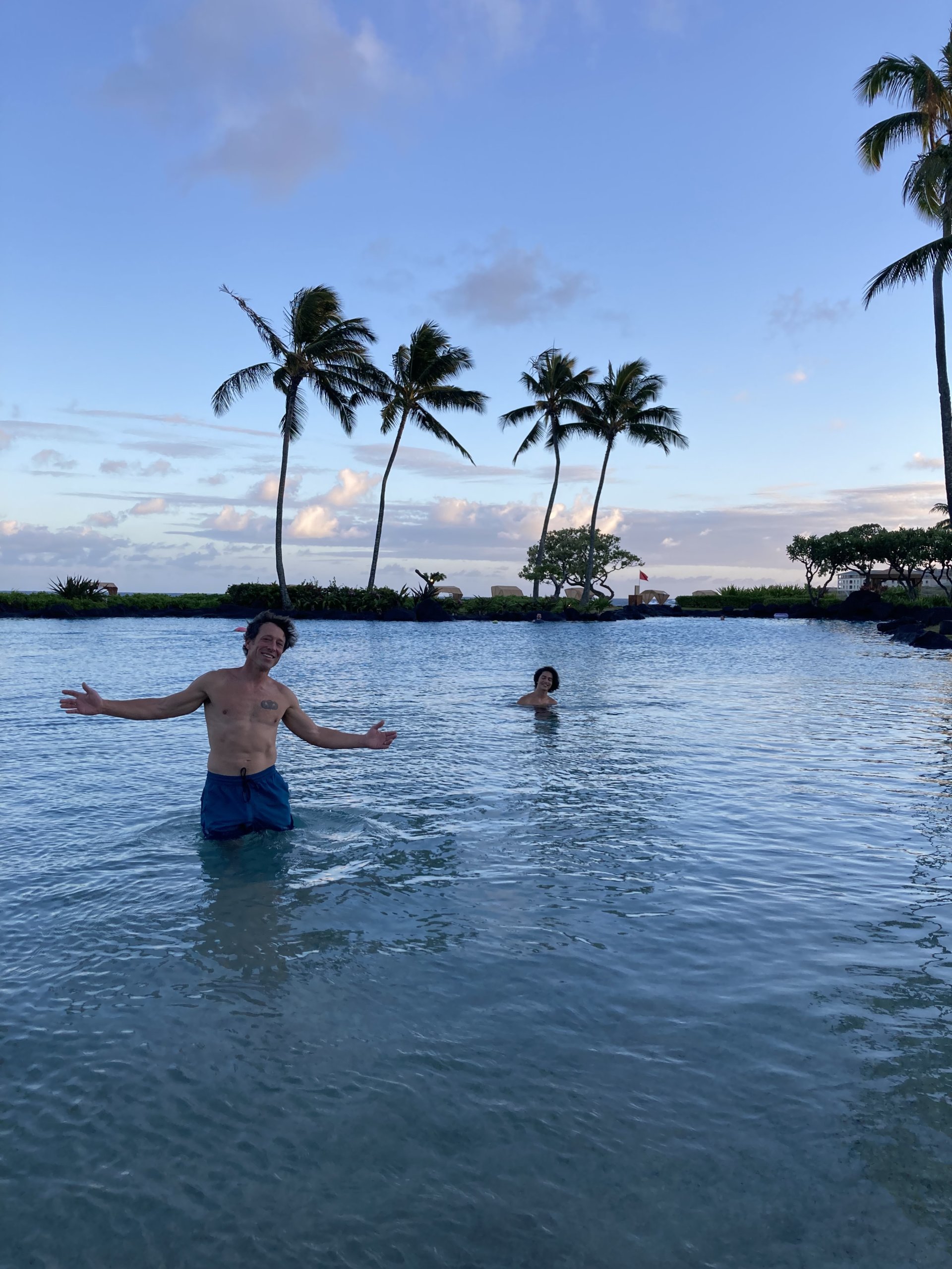 Two people in pool with palm trees in background
