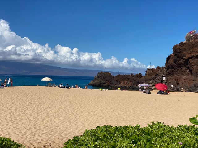 Large sandy area in front of water with rocks to the right