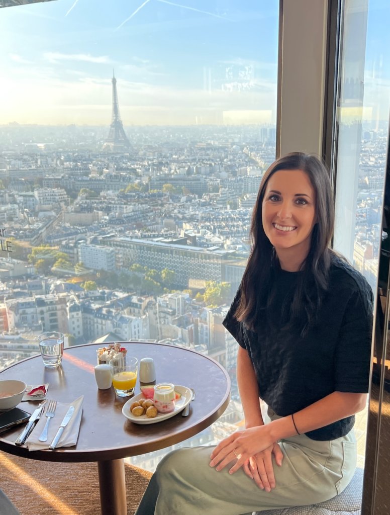 girl sitting in front of window with the Eiffel Tower in the background.