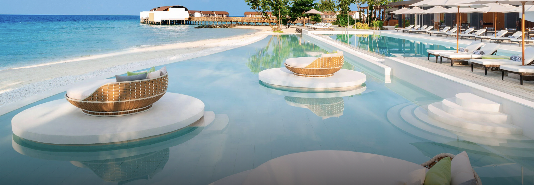 Pool near beach with chairs in middle of the pool