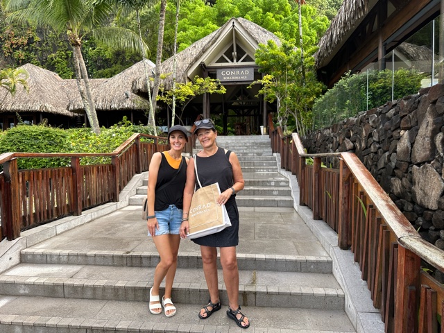 Two women on stairs with bag that says Conrad