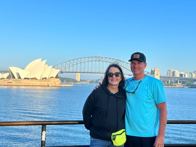 Man and woman in front of harbor and bridge