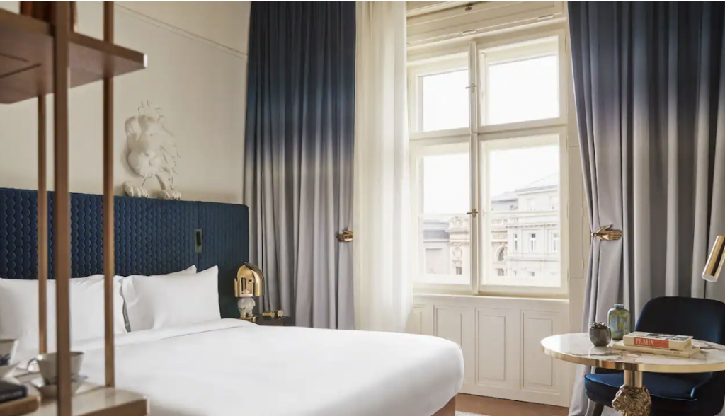 hotel room with grey drapes, white coverlet