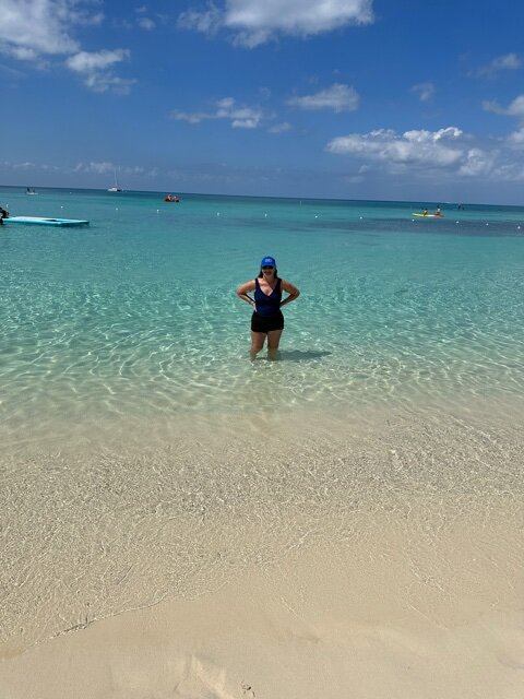 Woman in black bathing suit standing in turquoise water