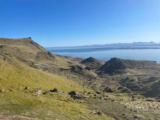 Green rolling hills along a body of water.