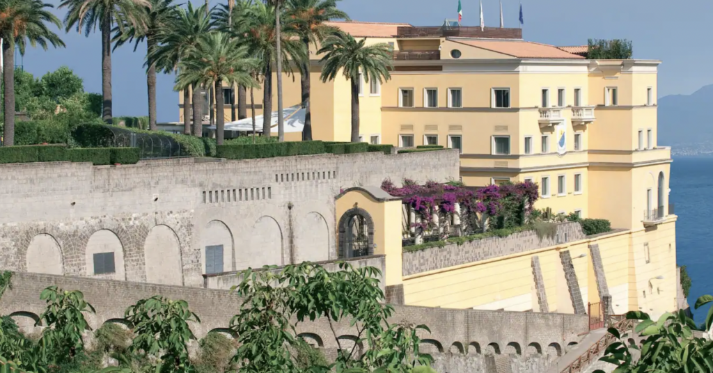 Large yellow hotel atop a hill with ocean views