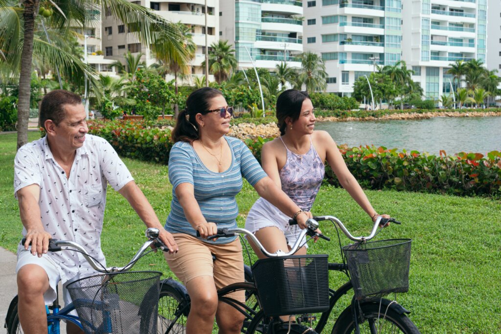 Man, woman, and teenage girl bicycling near tall buildings