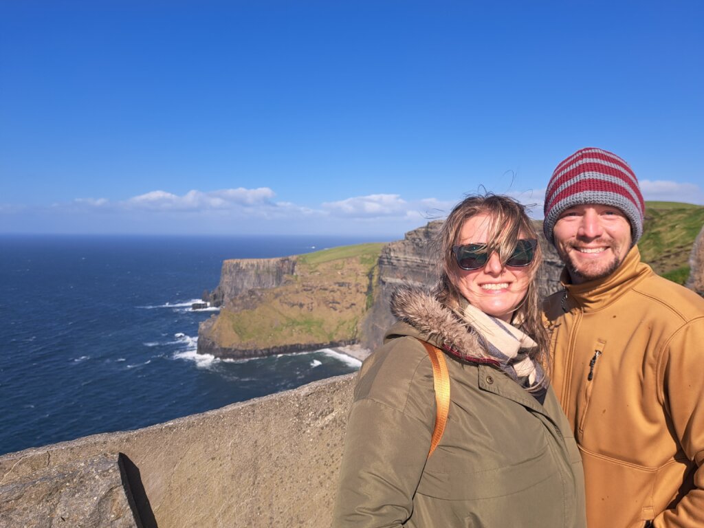 Man and woman standing in front of cliffs near water