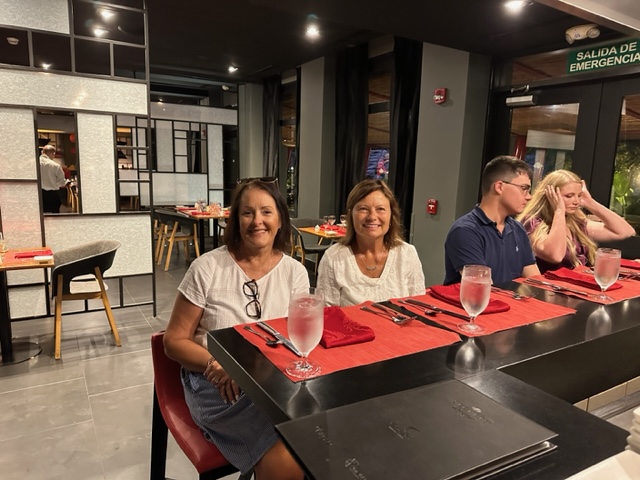 Two women sitting at high red top table