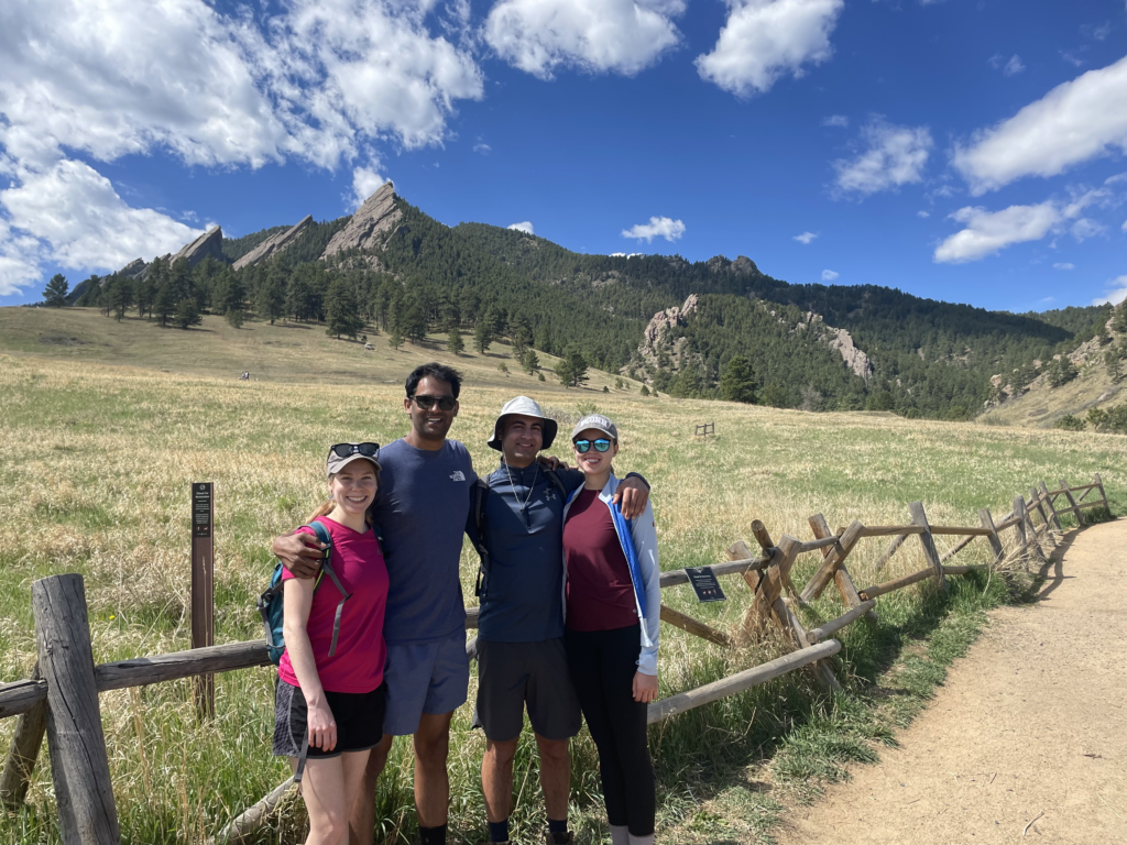 2 women and 2 men standing near mountains in front of fence.
