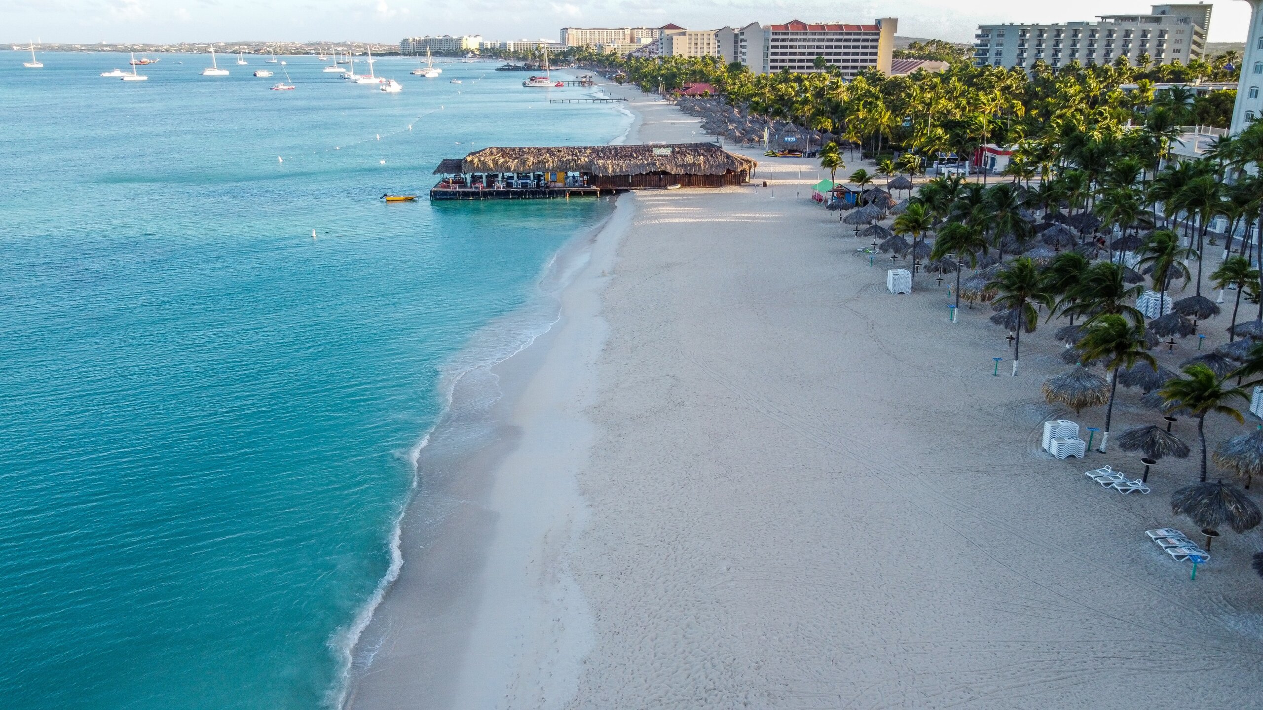 Row of hotels on white beach near blue water