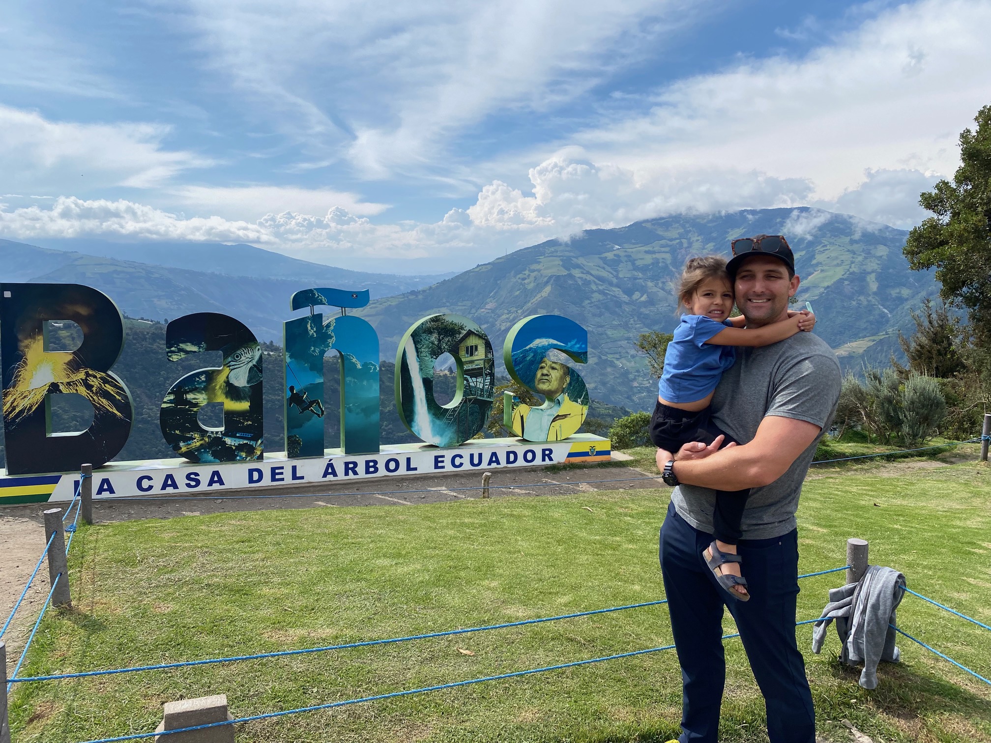 Man and young girl in front of Baños sign.