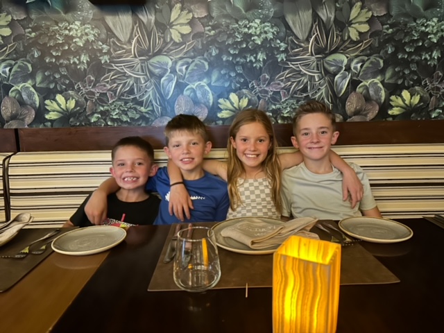 One girl and 3 boys with arms around each other.