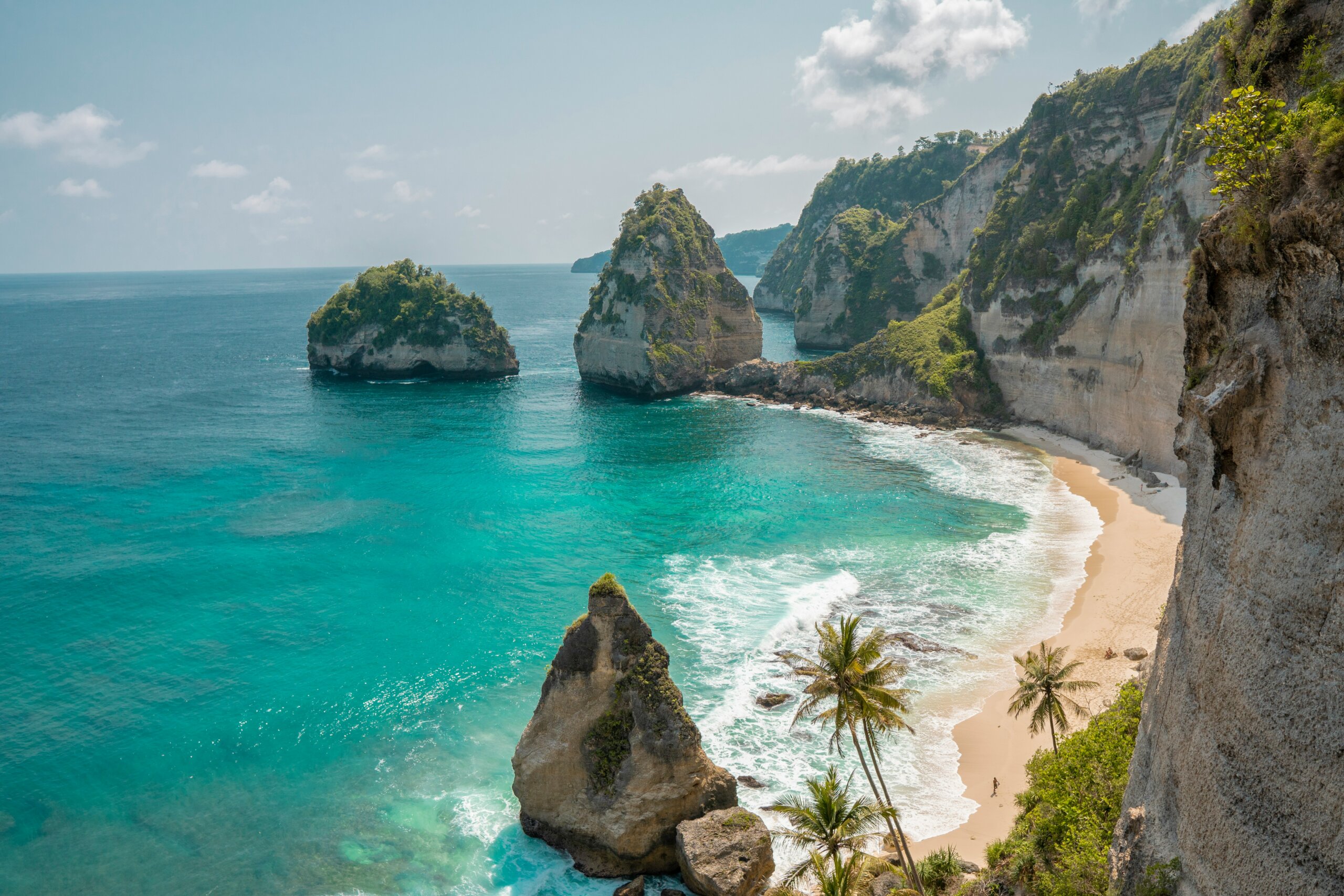 Large brown rocks near blue green water and sand