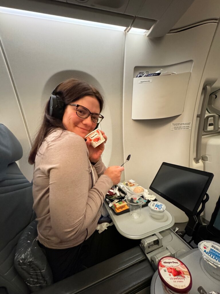 Women in airplane seat holding ice cream.
