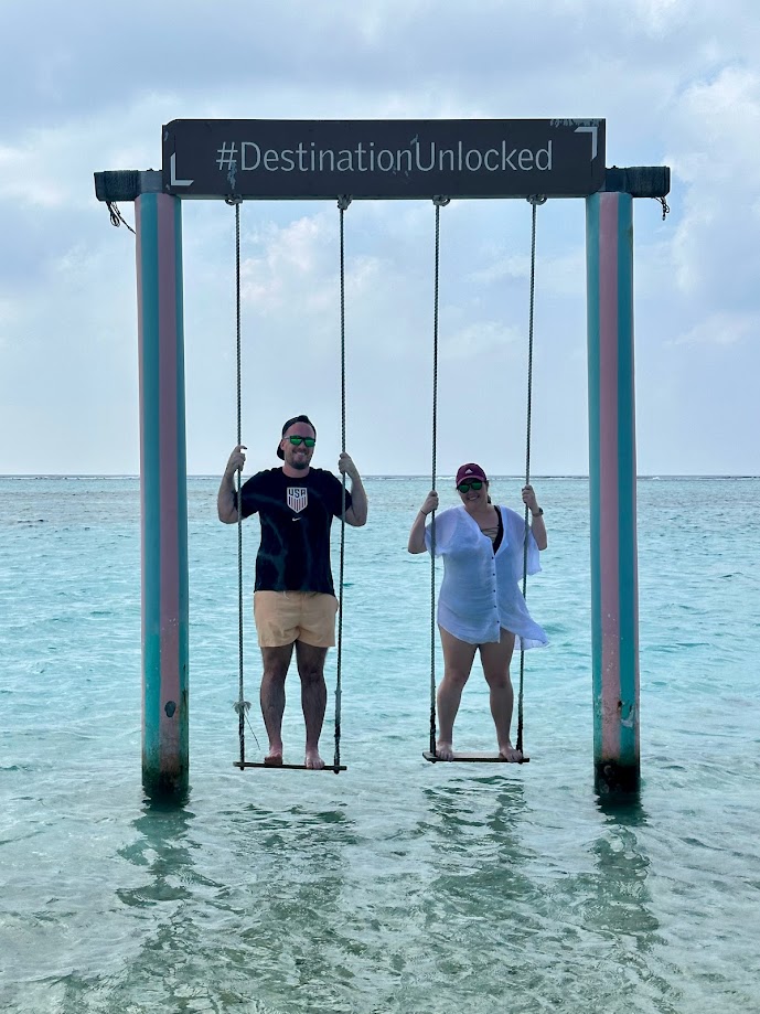 Man and woman standing on swings in blue green water