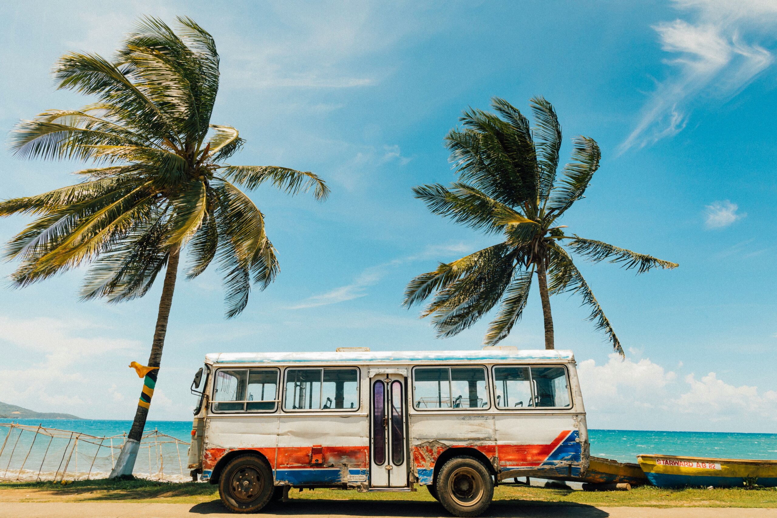 Colorful van parked on beach between two palm trees