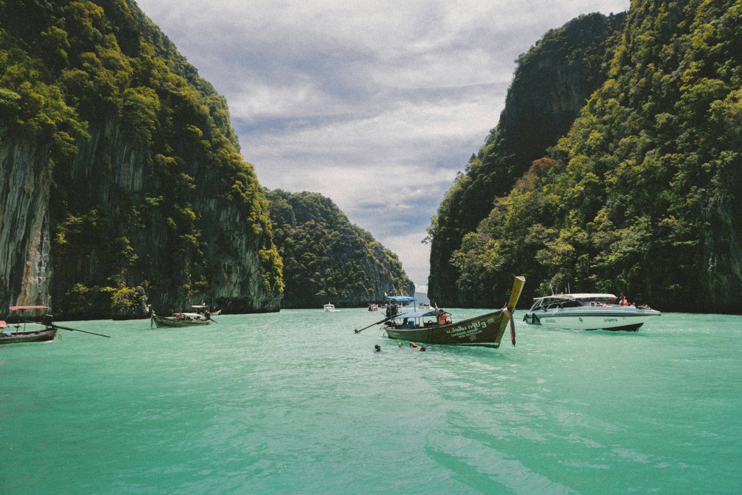 Longtail boats in water near rocks