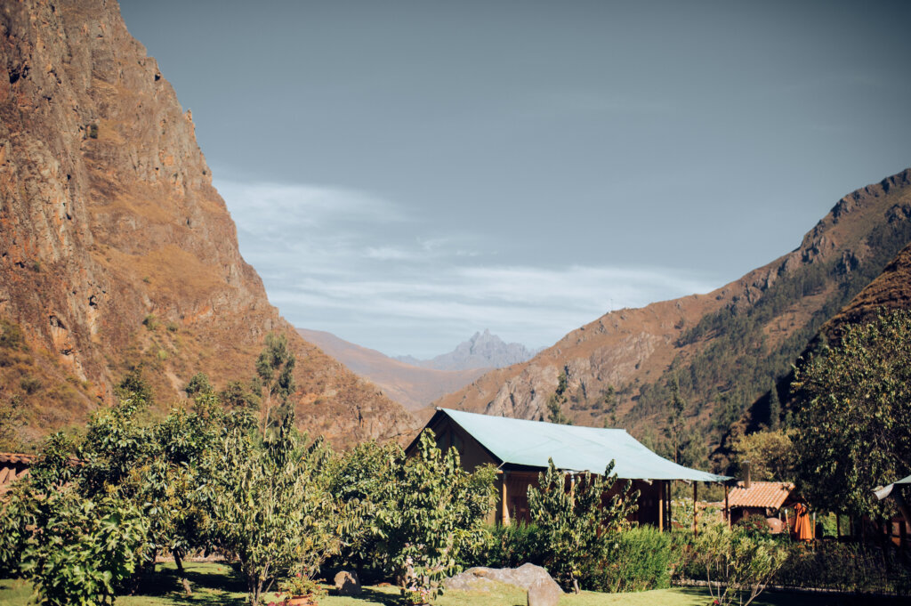 Safari-style tent surrounded by brown mountains and trees.