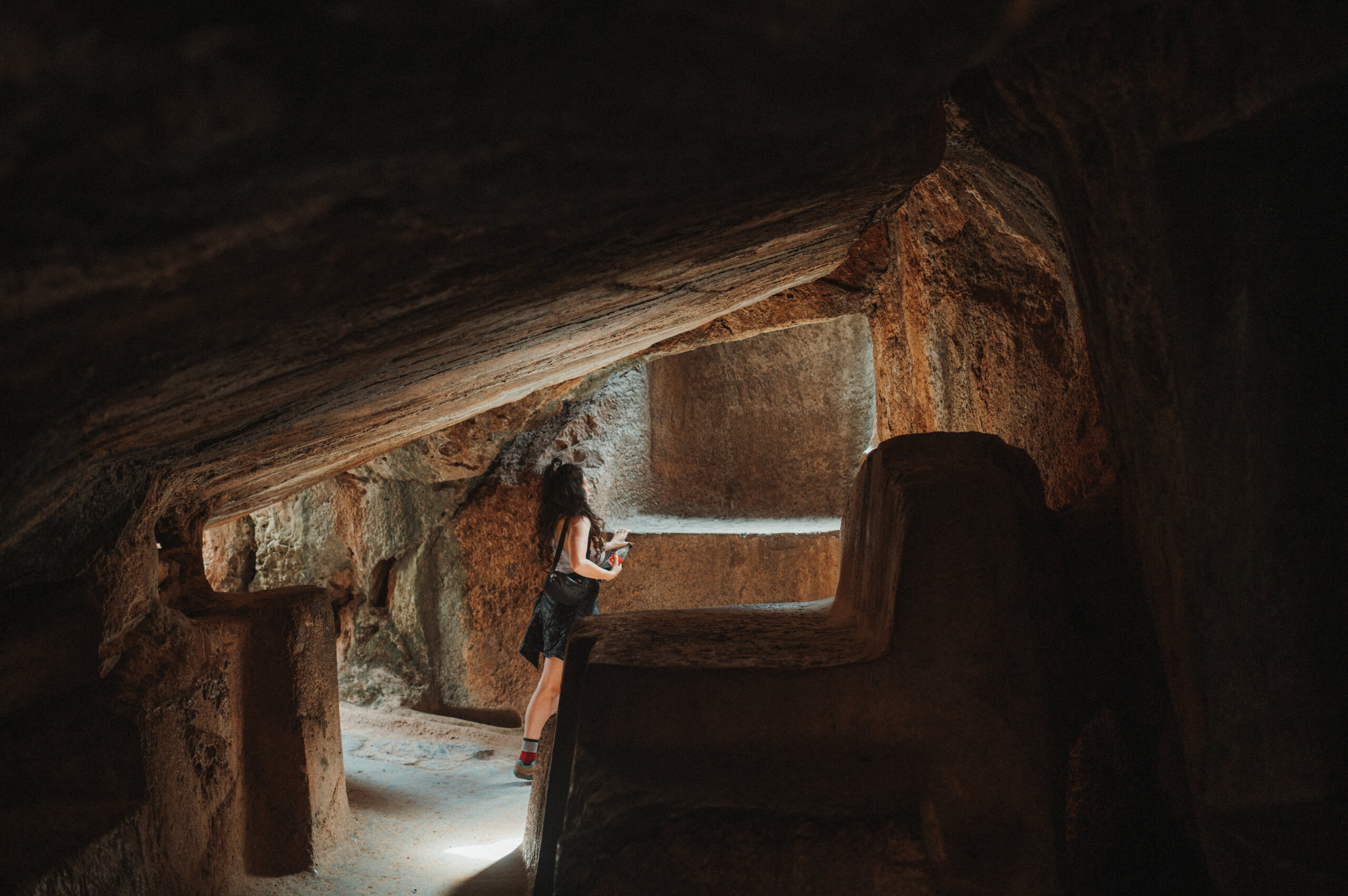Woman in a dark cave looking out toward the light