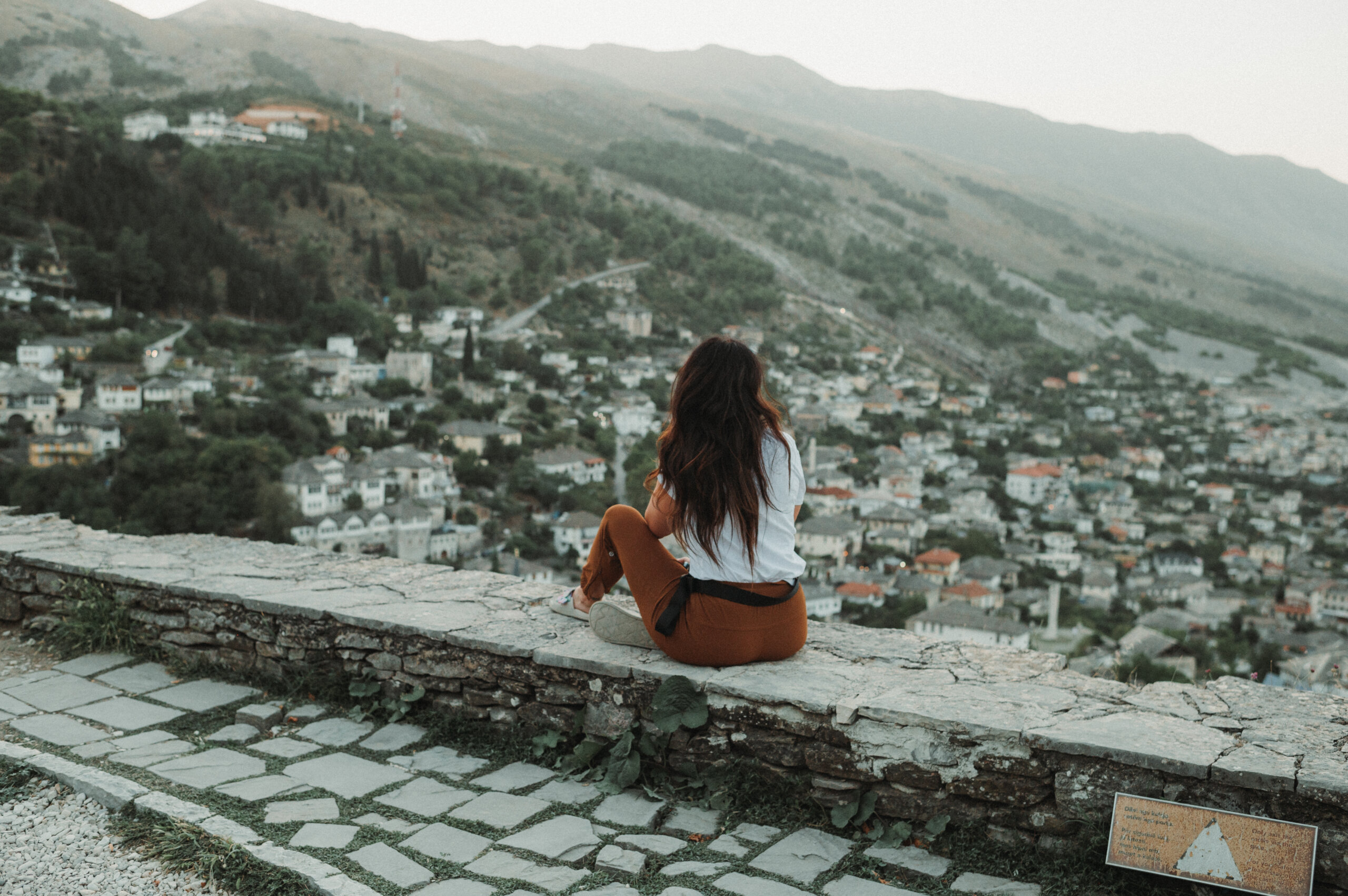 Woman sitting on wall overlooking old European city