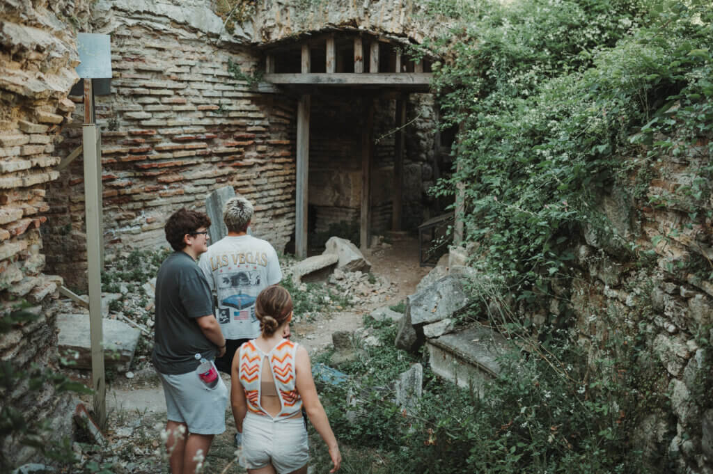 Three young people wandering around ancient Roman ruins