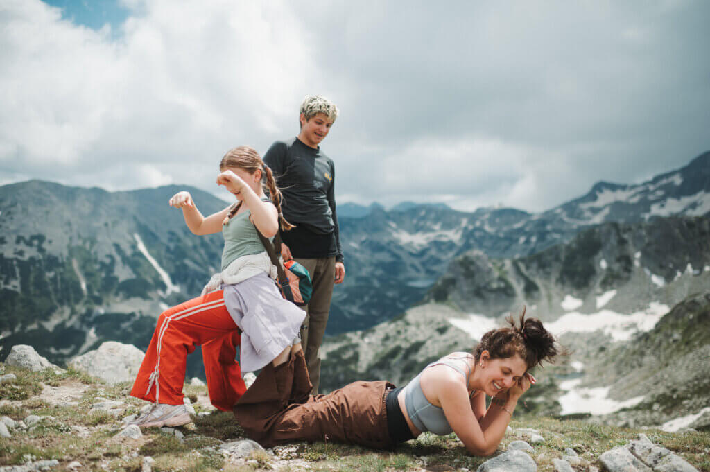 Three people posing on a peak with mountains in the background
