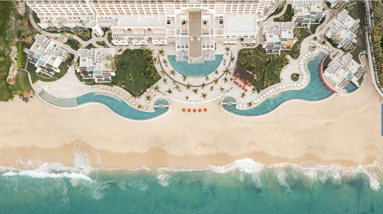 Aerial view of the massive Marquis Los Cabos All Inclusive Resort & Spa surrounded by sand and blue water.