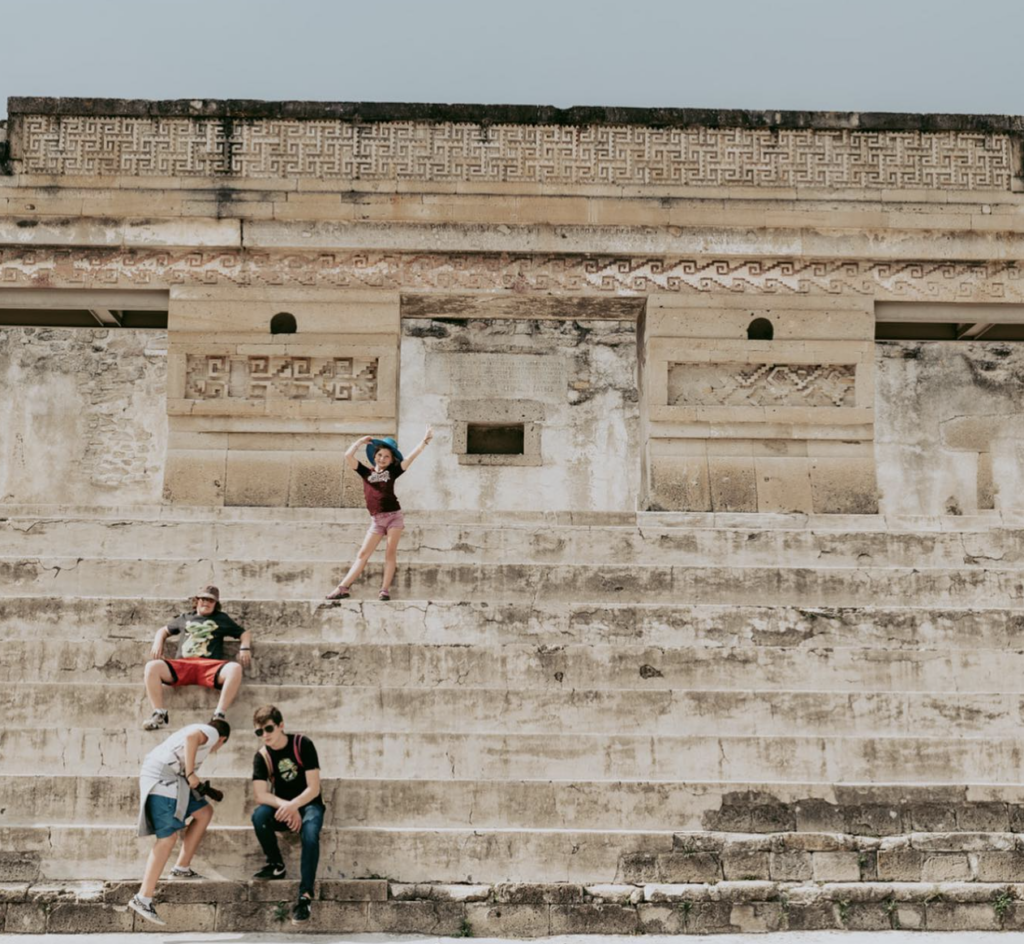 Four young children climbing stone steps on ancient ruins.