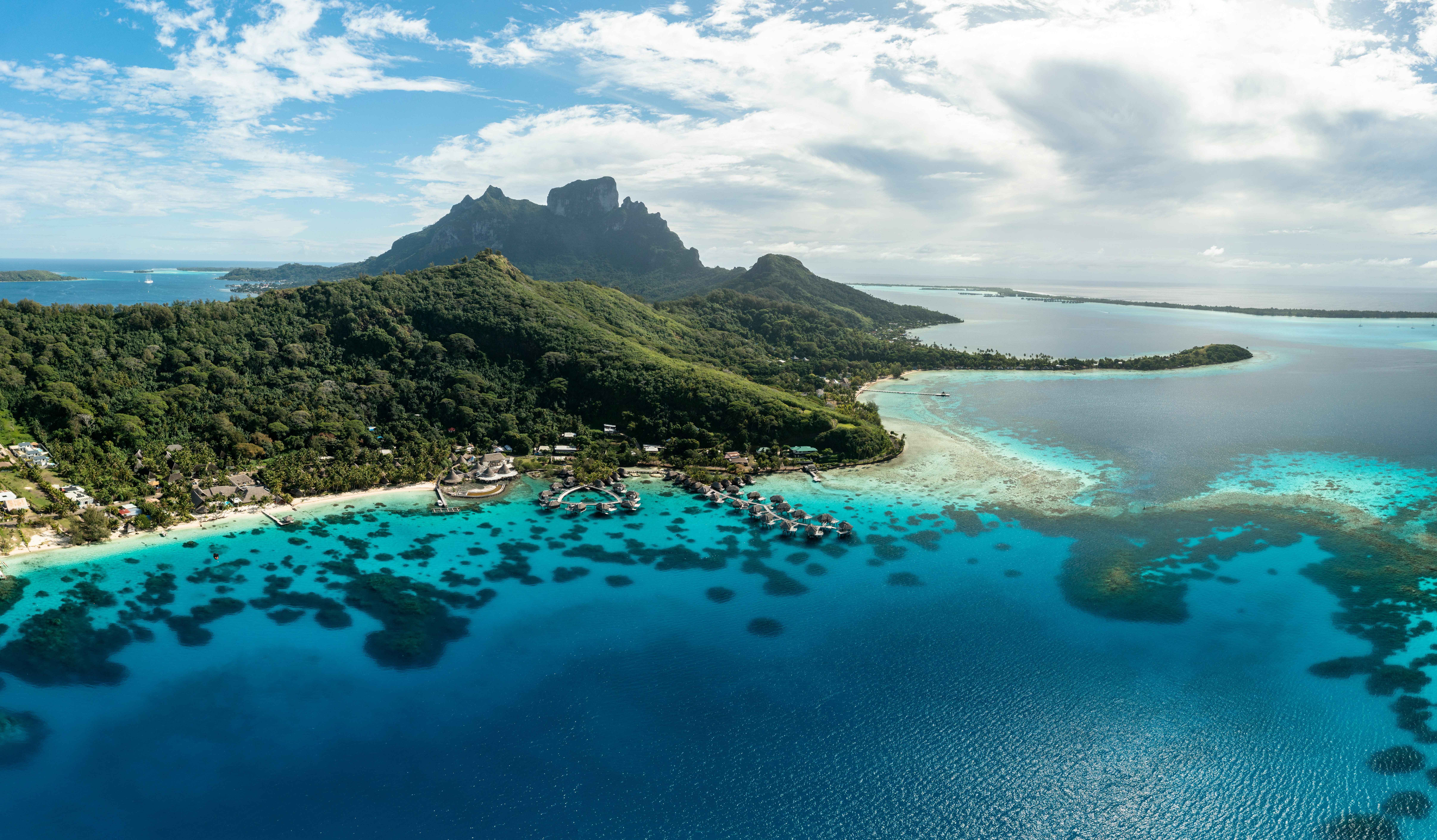 An aerial view of a mountainous island in the middle of a bright blue sea