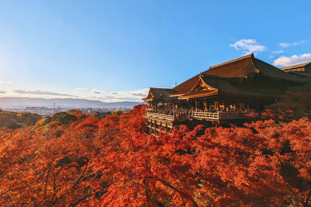 Fiery fall colors surrounding building on a hill in Kyoto