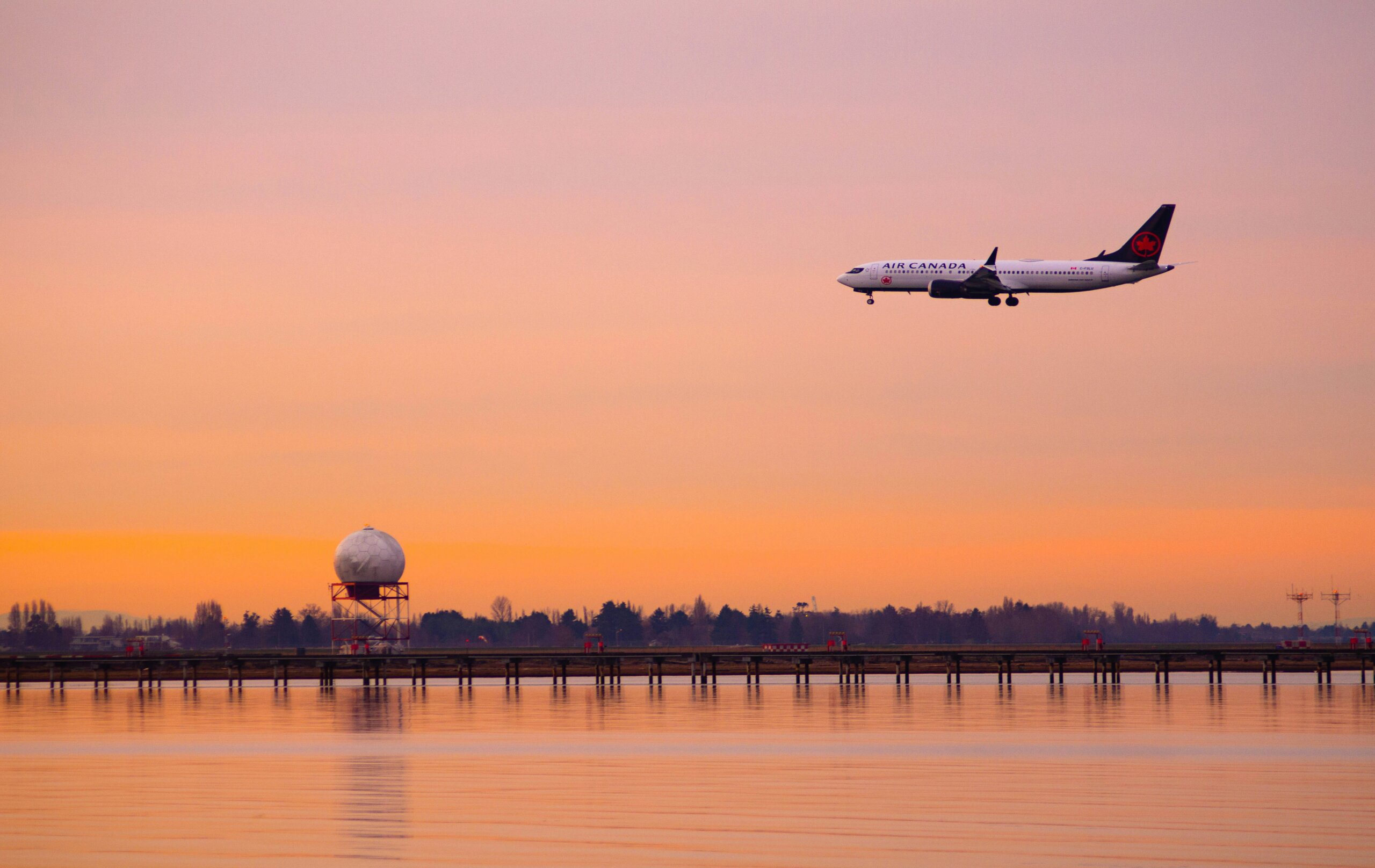 Air Canada airple flying over a city at sunset