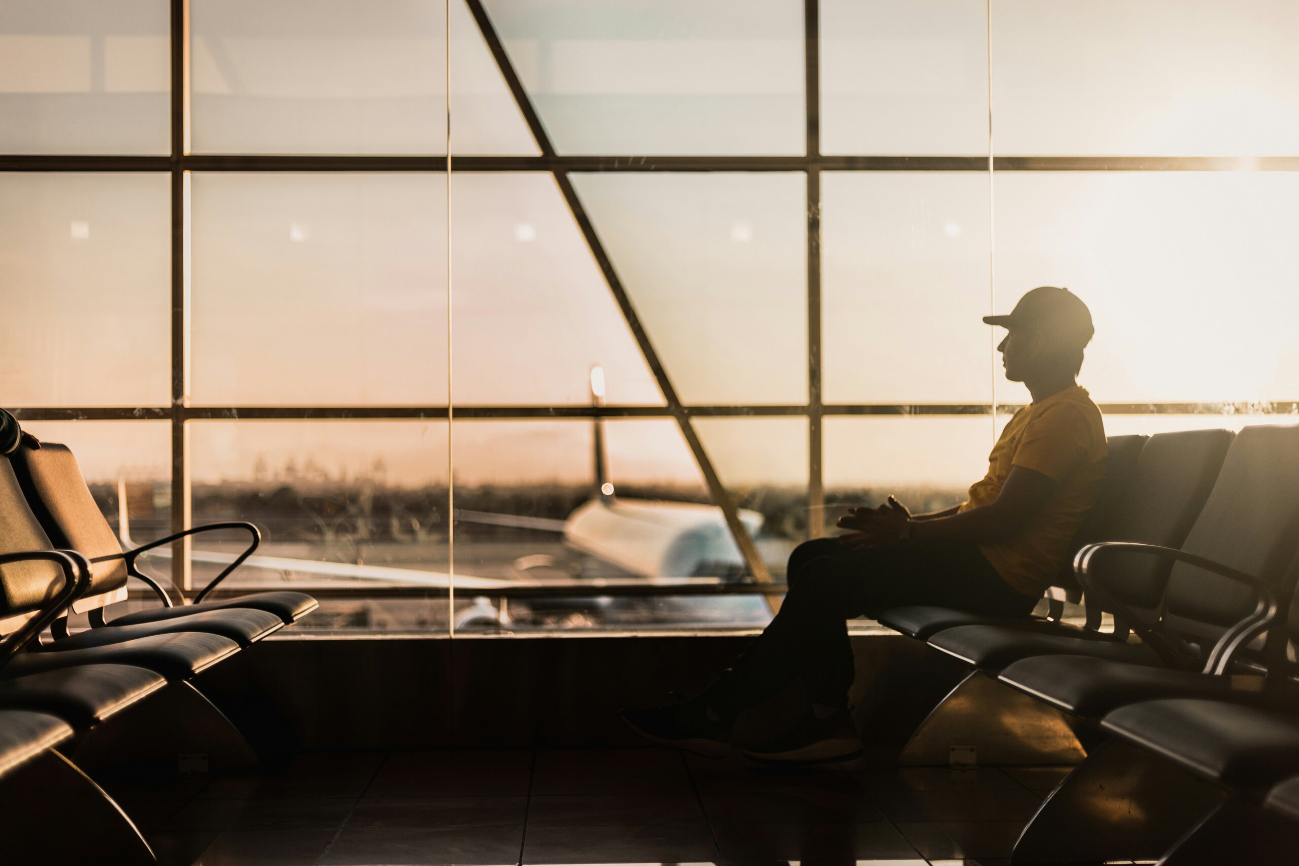 Man waiting at the gate in an airport at sunset