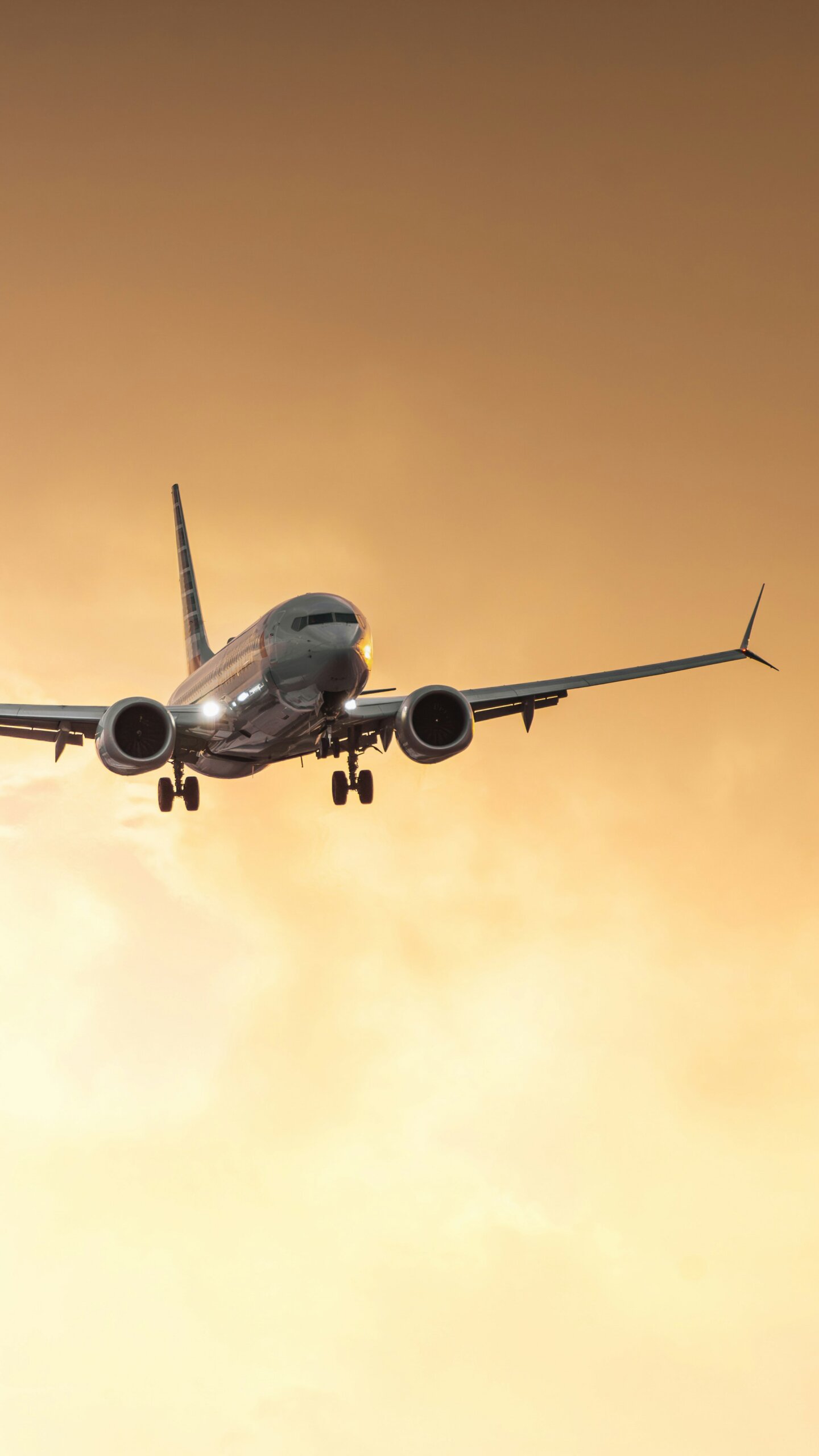 Airplane flying through the sky at sunset.