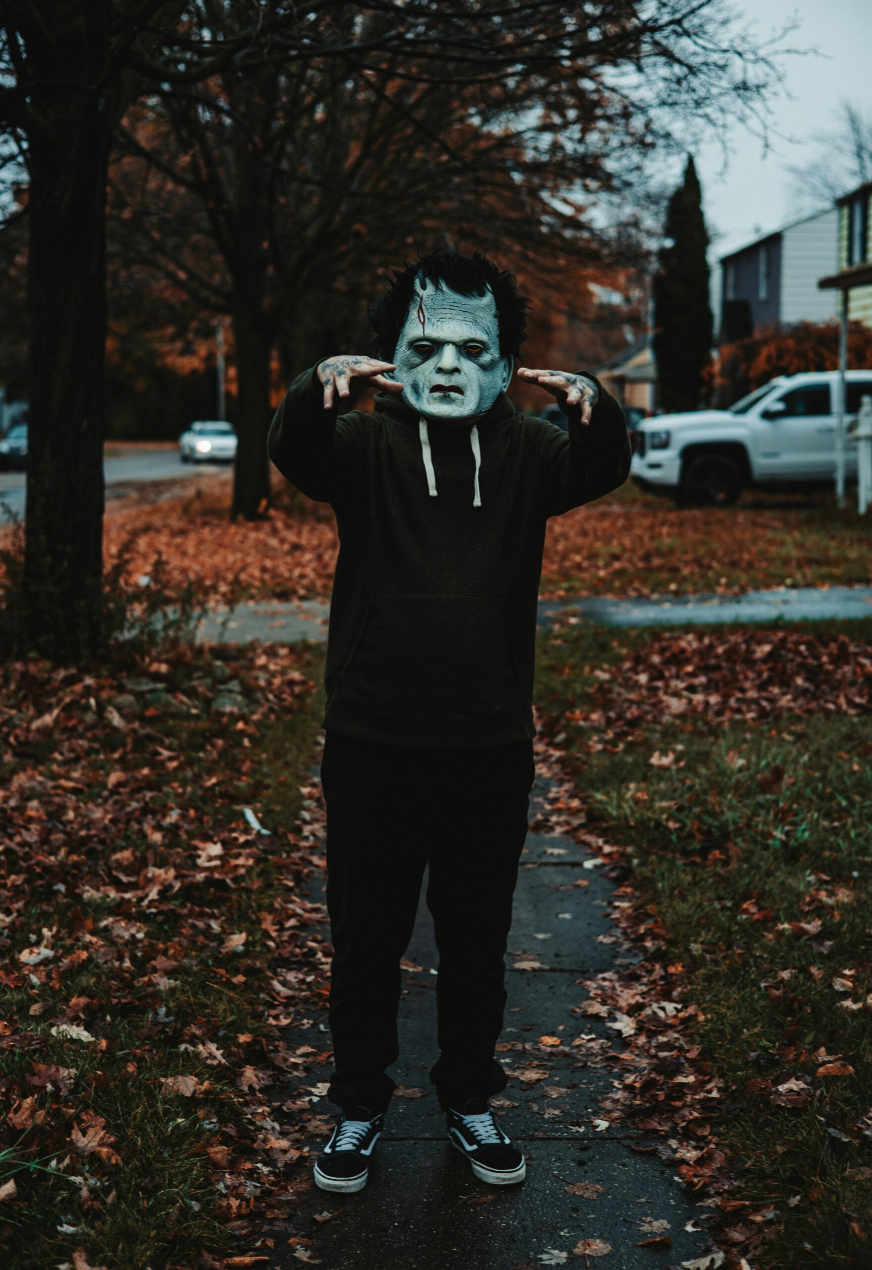 Child in frankenstein costume in front of leafy fall neighborhood